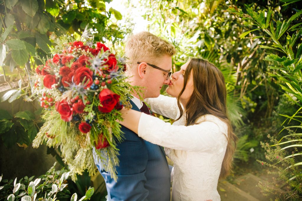 Jackson Hole wedding photographer captures Bride kisses nose of groom in greenhouse