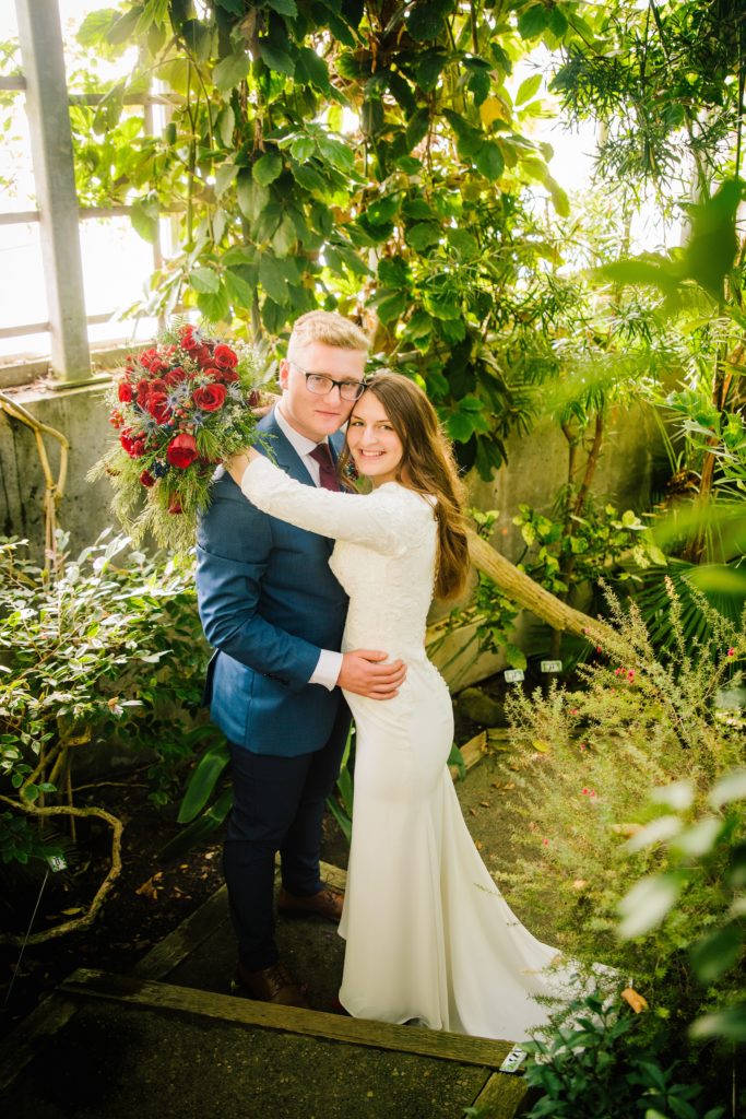 Jackson Hole wedding photographer captures bride and groom embracing during greenhouse portraits