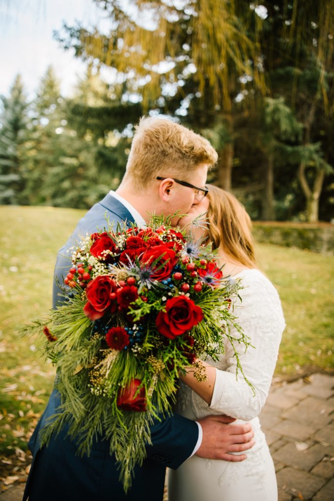 Jackson Hole wedding photographer captures bride kissing with wedding bouquet