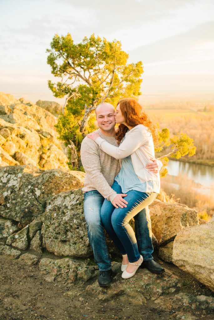 Jackson Hole wedding photographer captures couple sitting on rock wall embracing
