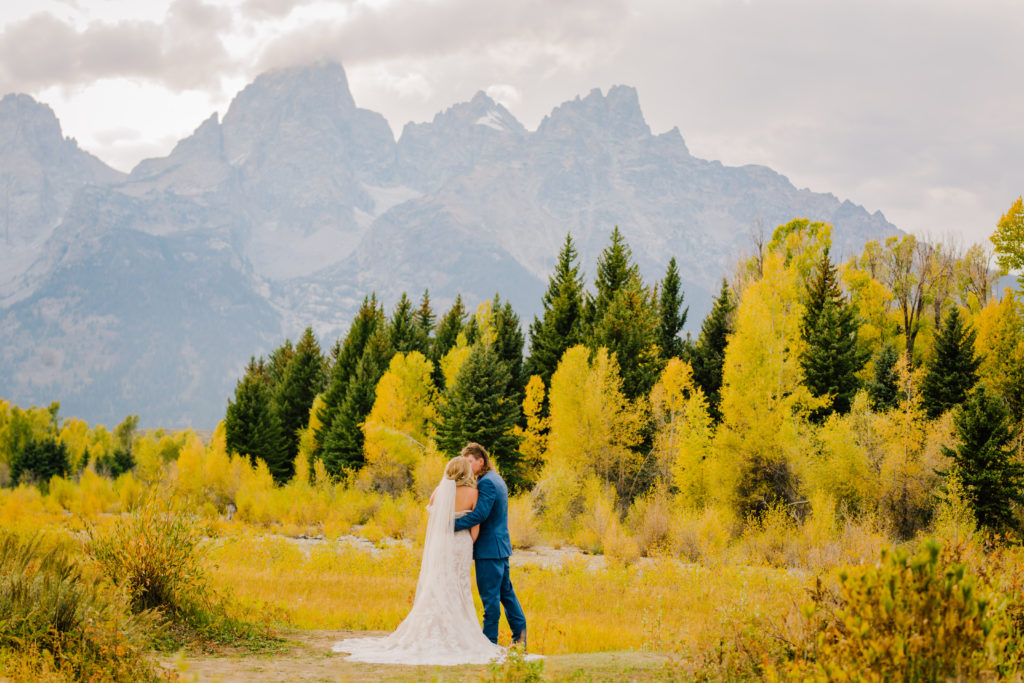outdoor jackson hole wedding with bride and groom kissing in a field 