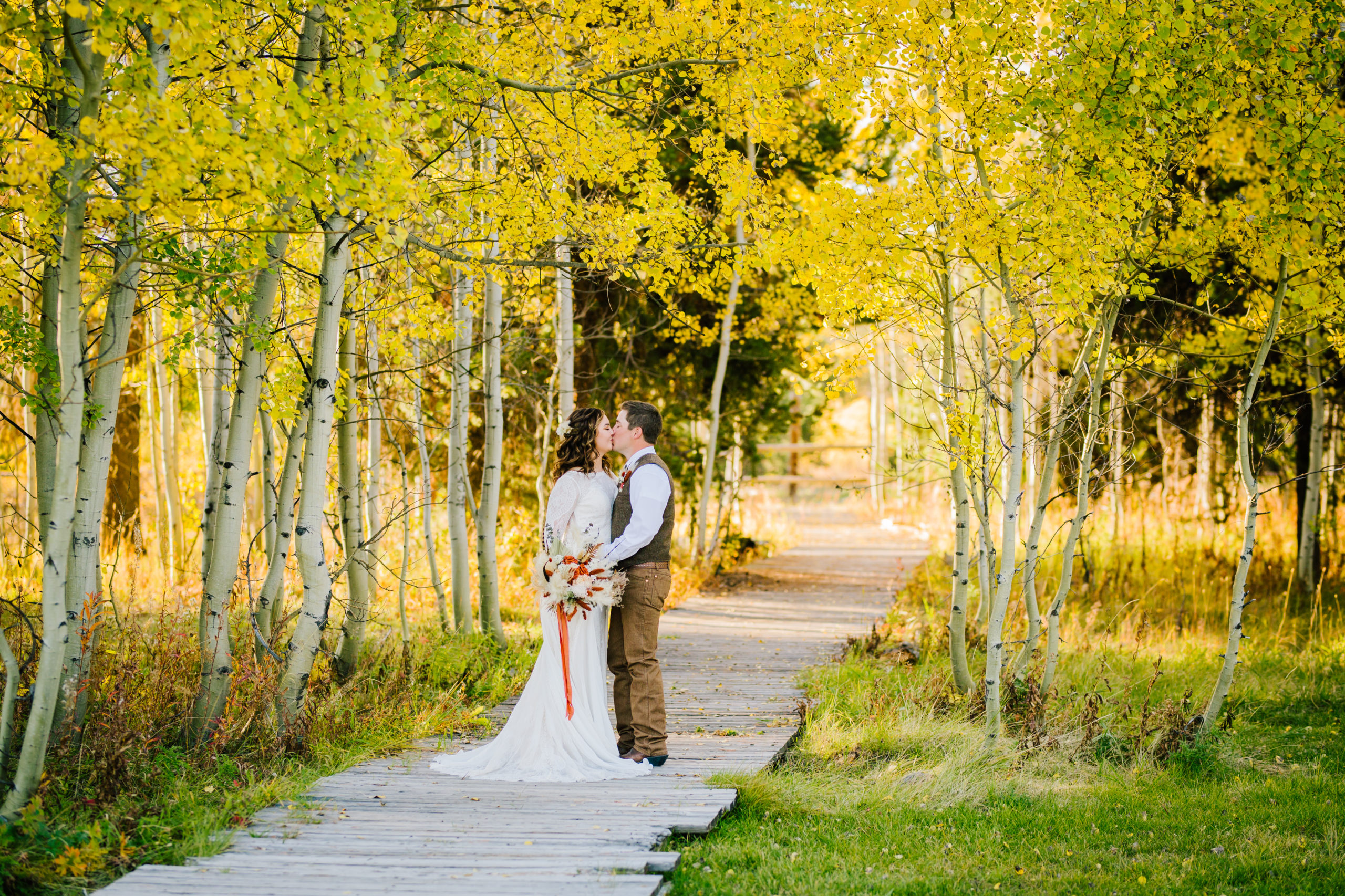 bride and groom on a path in the woods during their fall wedding in Yellowstone