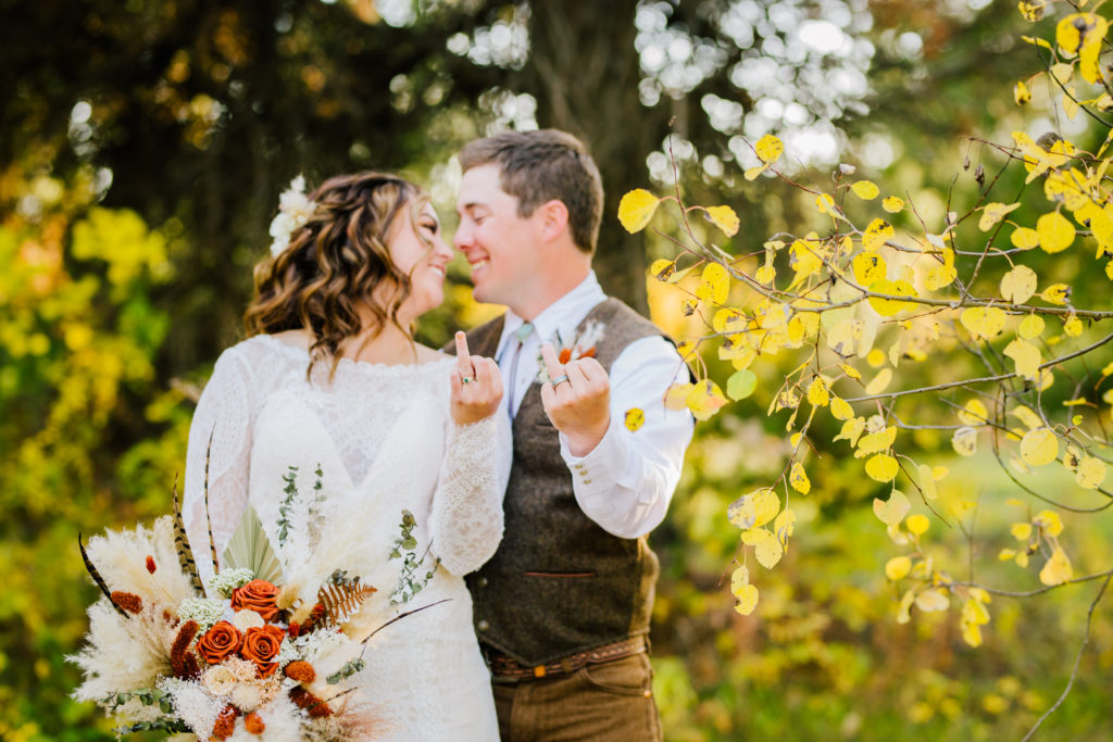 bride and groom holding up ring fingers at wedding after using wedding planning tips