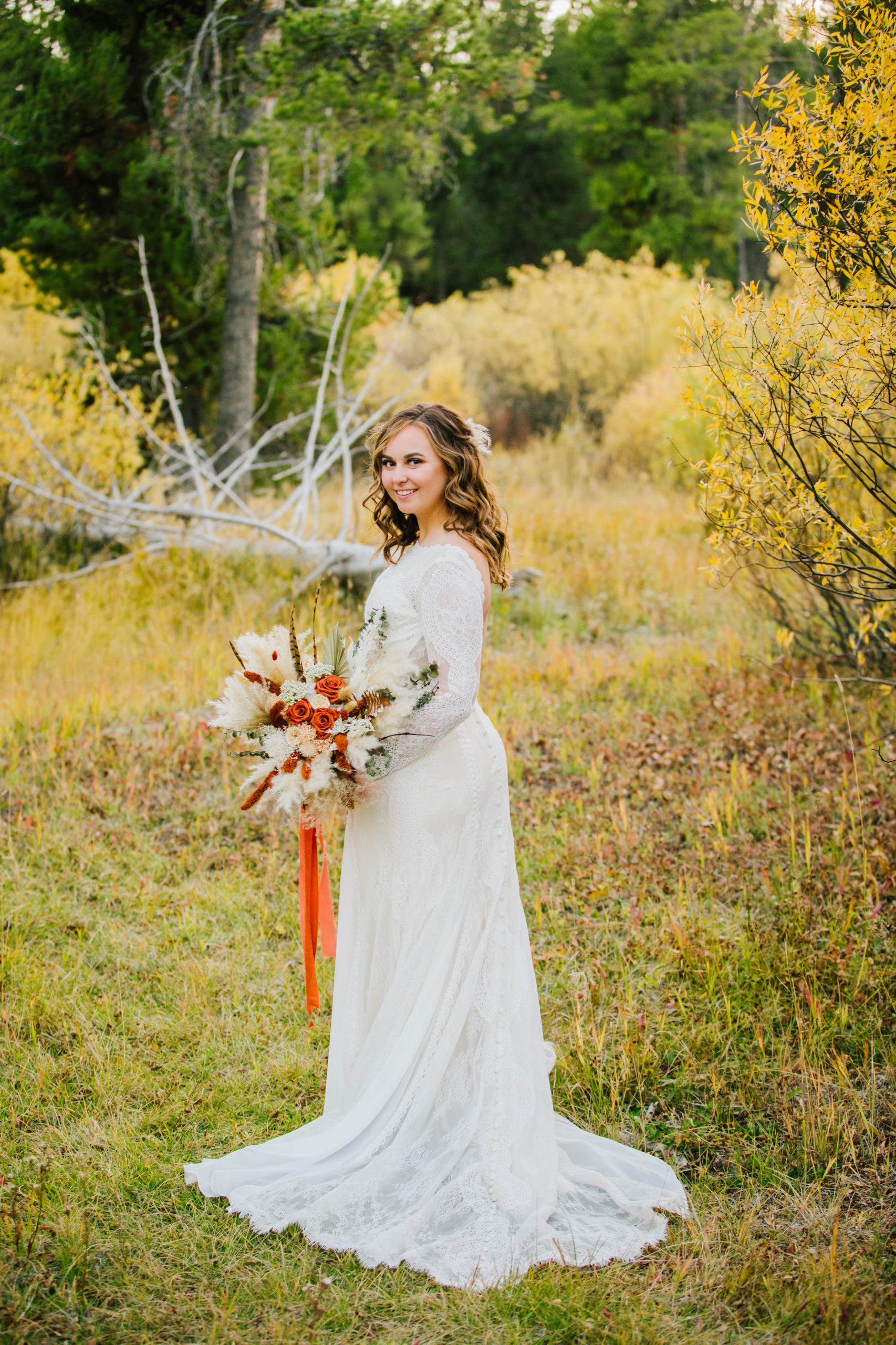 outdoor fall bridals with bride holding her wedding bouquet and looking over her shoulder