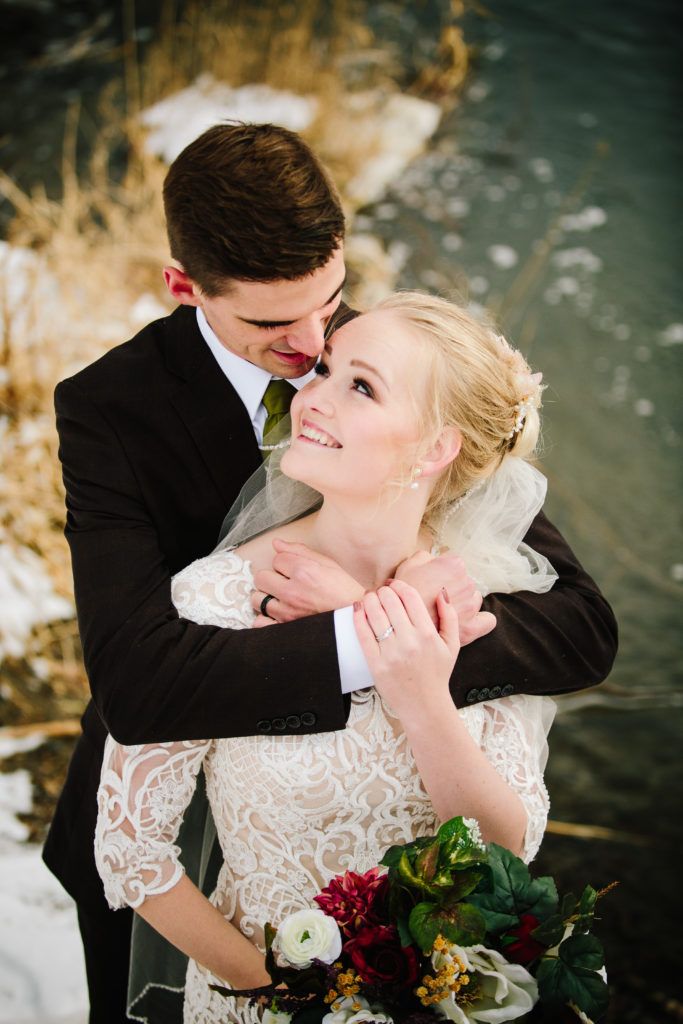 Jackson Hole wedding photographer captures bride and groom embracing during snowy pocatello portraits