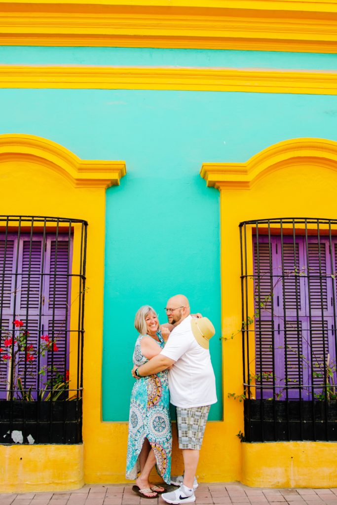 Jackson Hole wedding photographers captures Yellow and teal house with couple kissing in front of it. 