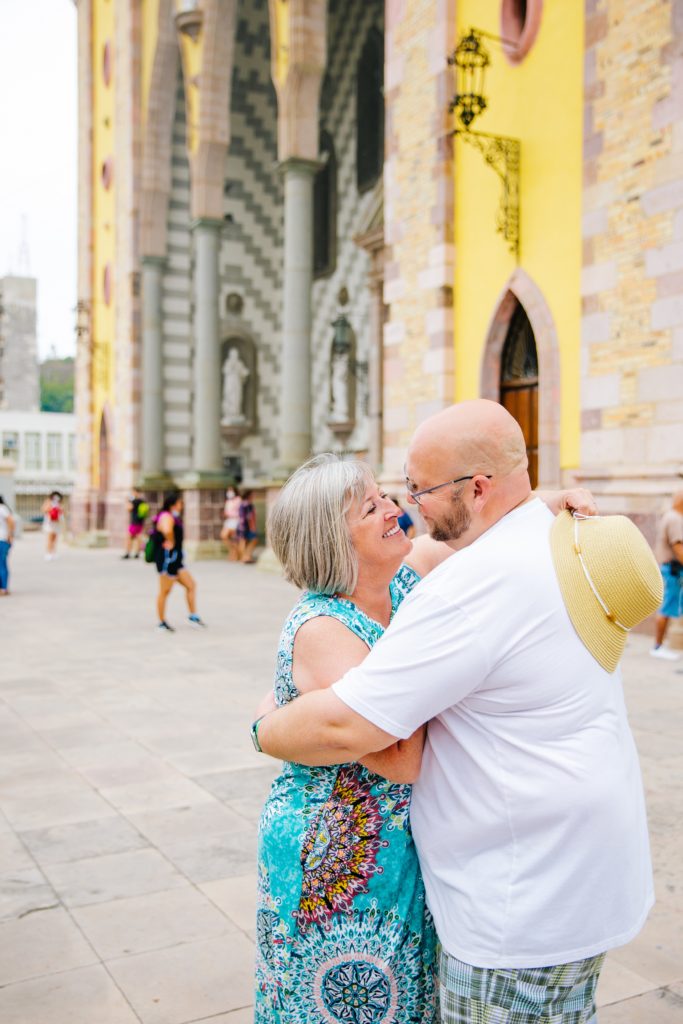 Jackson Hole wedding photographer captures engaged couple hugging in front of mazatlan church