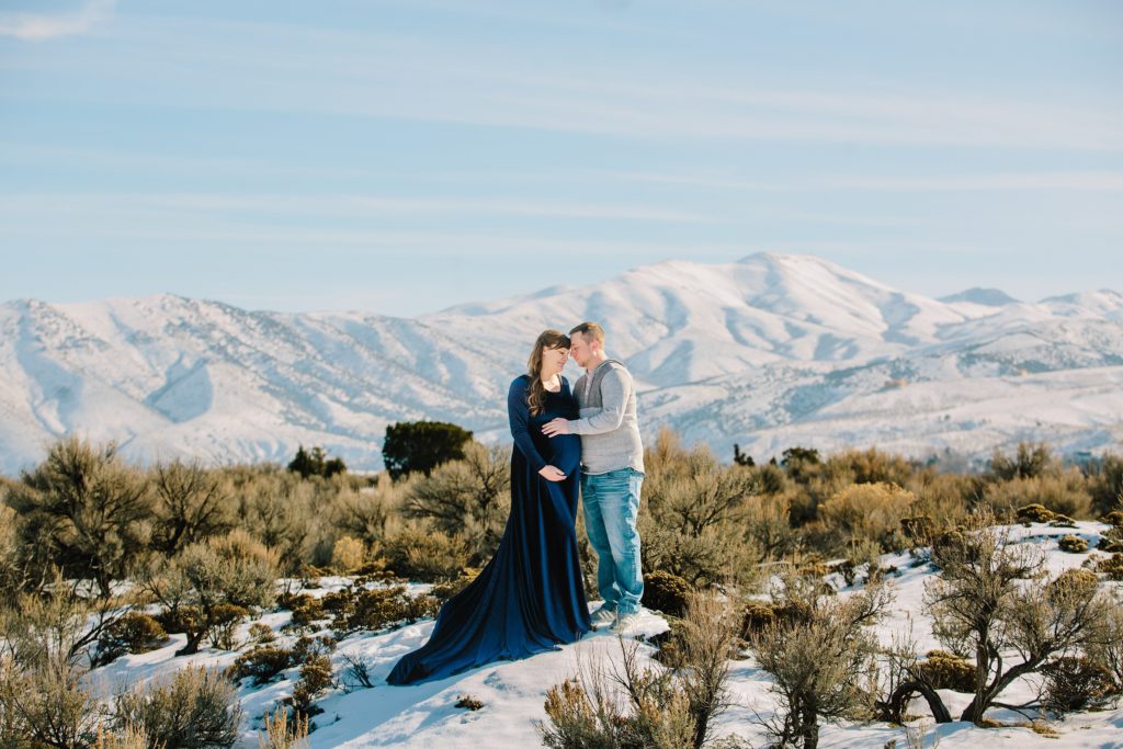 Jackson Hole wedding photographer captures couple standing in snowy area taking maternity pictures