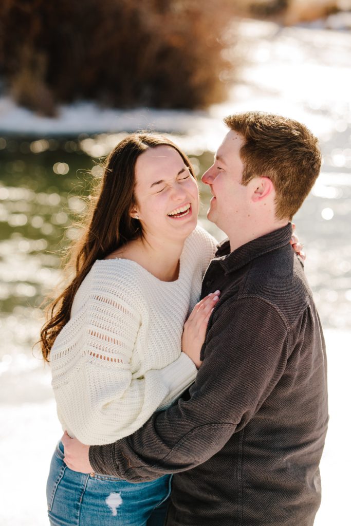 Jackson Hole wedding photographer captures man and woman laughing during snowy engagement session