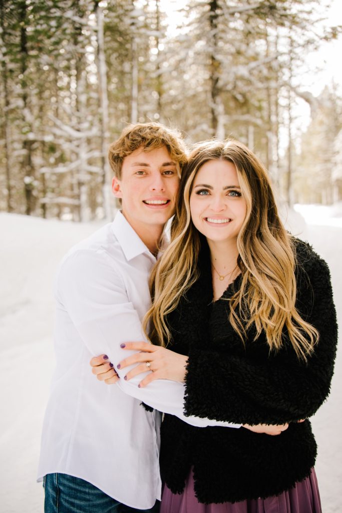 Jackson Hole wedding photographer captures couple hugging during snowy engagement portraits