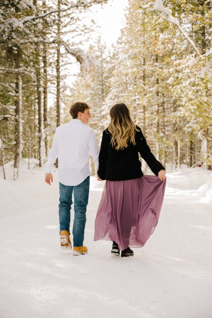 Jackson Hole wedding photographer captures couple walking away during snowy engagements