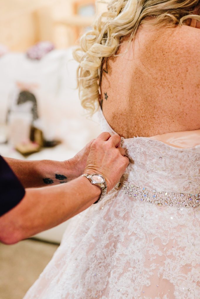 Jackson Hole wedding photographer captures mom doing the buttons oh a brides dress