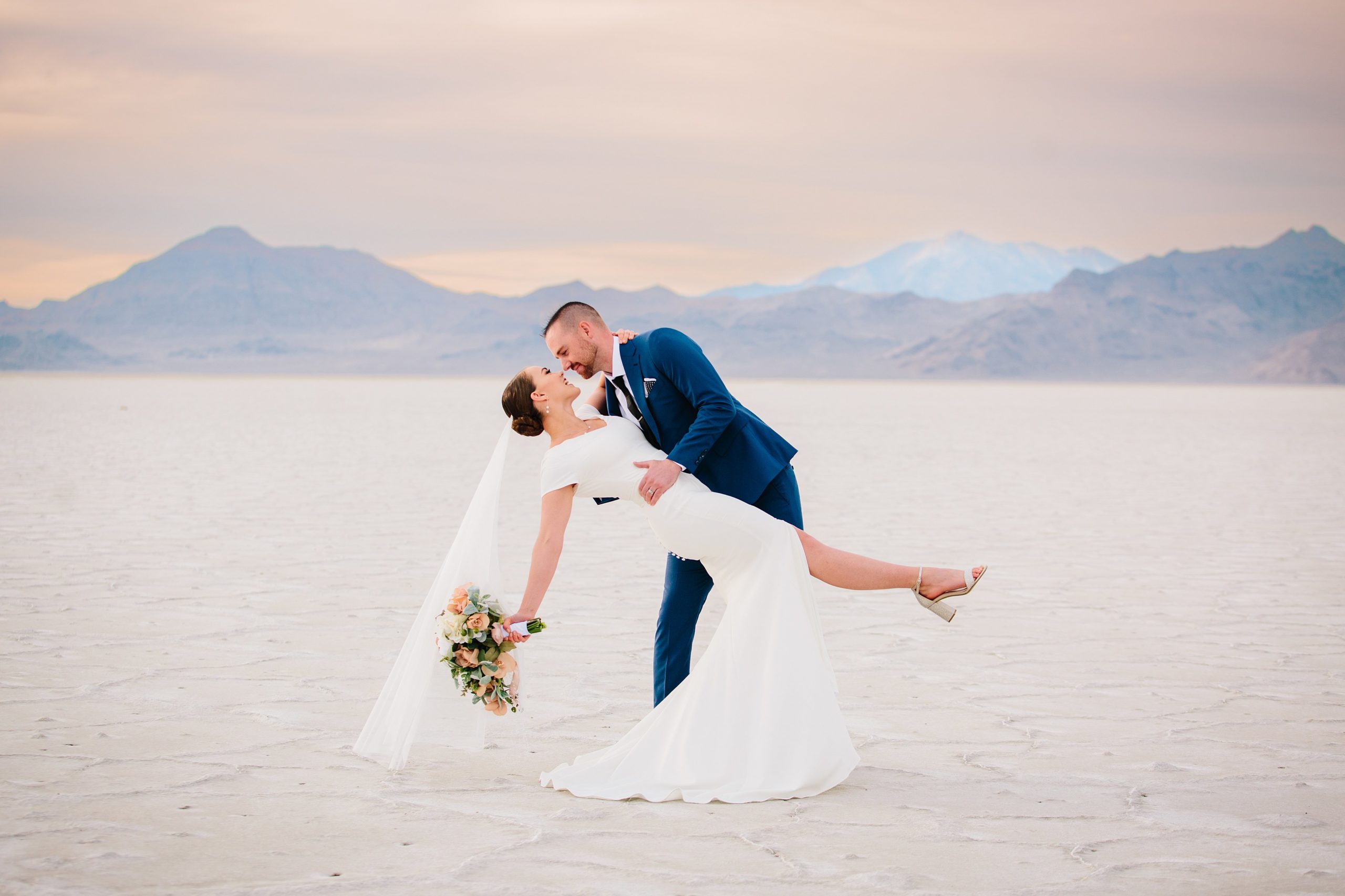 Jackson Hole wedding photographers capture bride and groom dip kissing in salt flats bridals