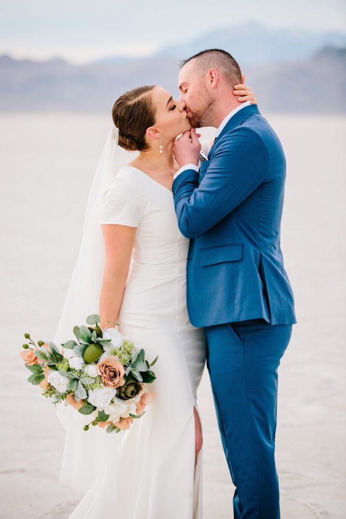 Jackson Hole wedding photographer captures Bride and groom embrace in kiss at utah salt flats