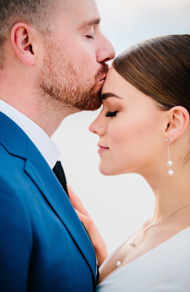 Jackson Hole wedding photographer captures groom kissing brides head at bonneville salt flats in utah