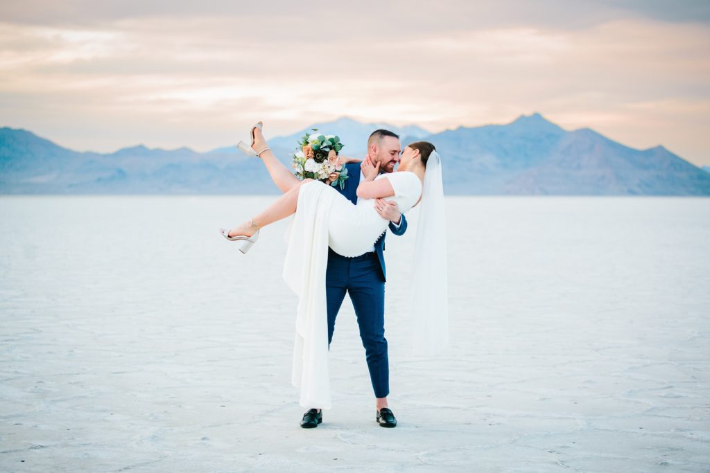 Jackson Hole wedding photographer captures groom lifting bride up and kissing her