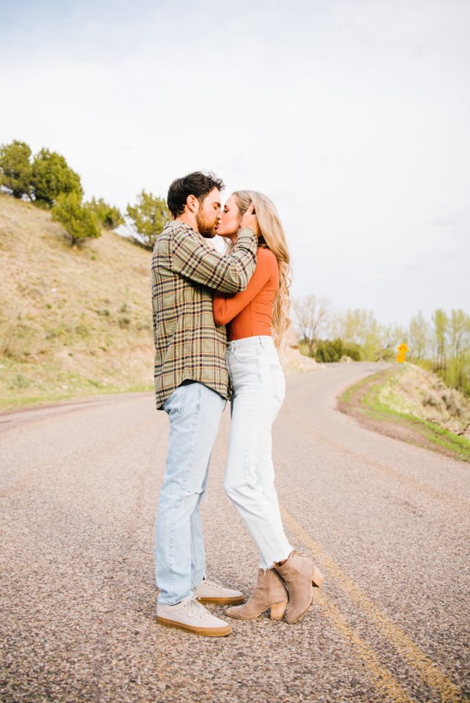 Jackson Hole wedding photographer captures Kissing couple in middle of road wearing orange and green