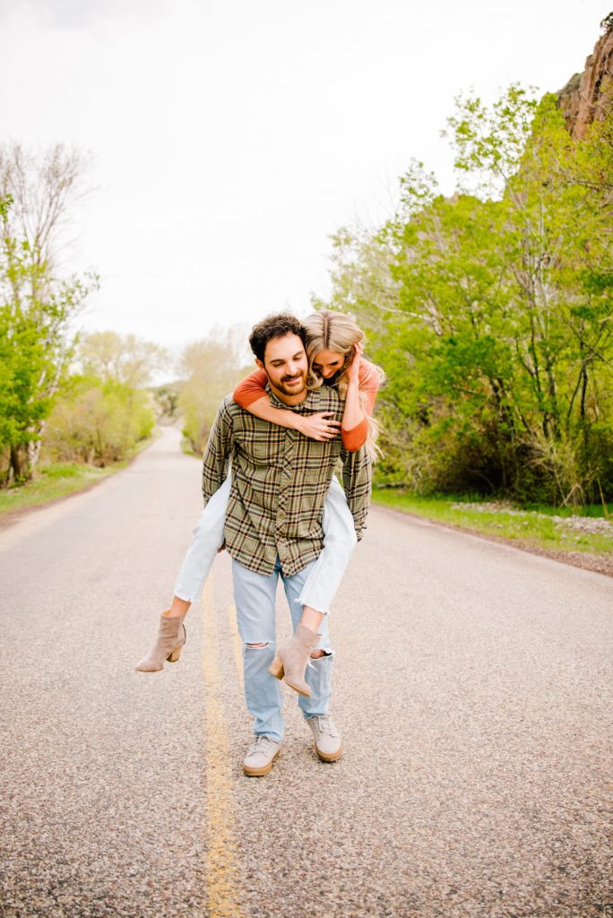 Jackson Hole wedding photographer captures Couple piggy back ride laughing in middle of