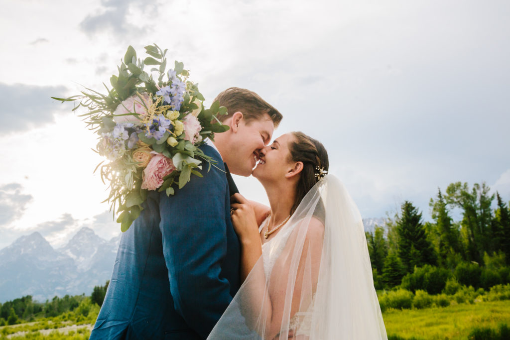 bride and groom kissing in Jackson Hole while bride holds bouquet