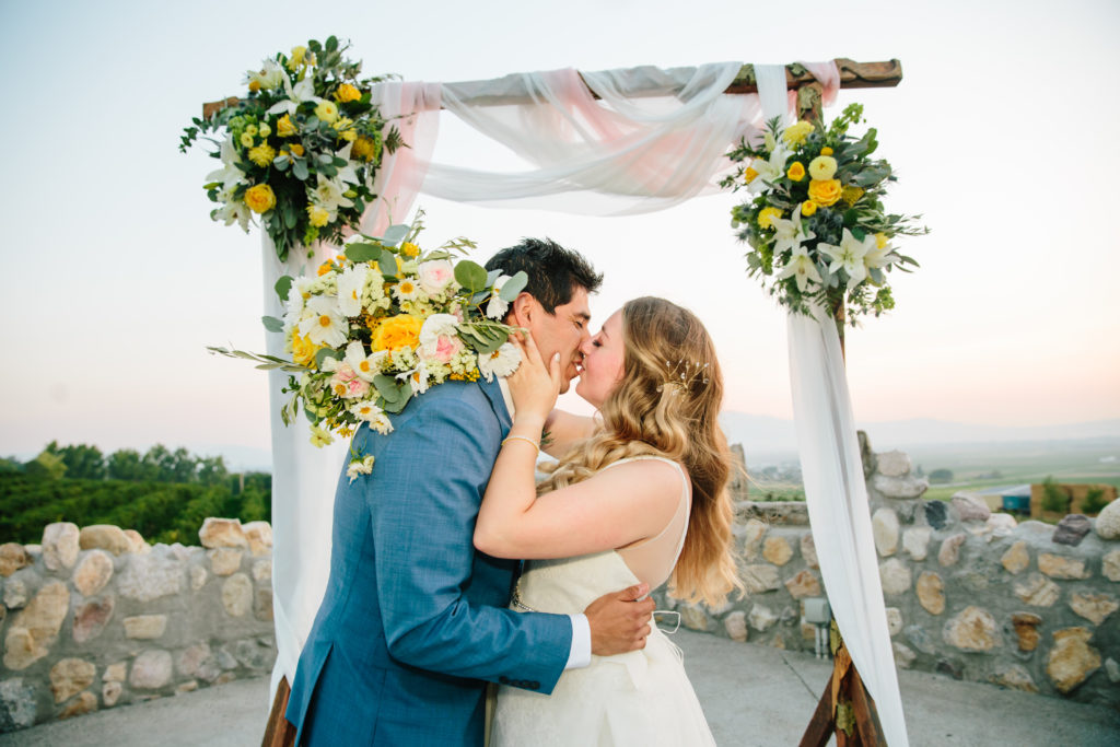 bride and groom kissing at alter during summer weddings