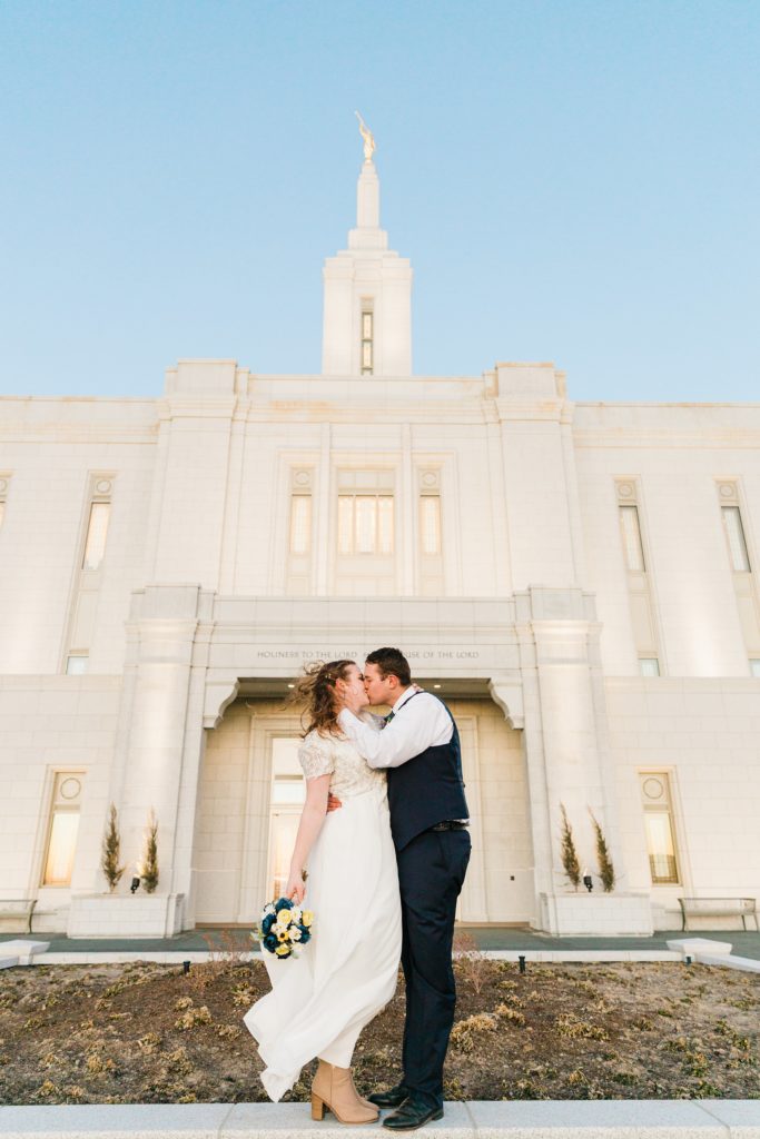 Jackson Hole wedding photographer captures Bride and groom kiss outside of pocatello lds temple in the cold