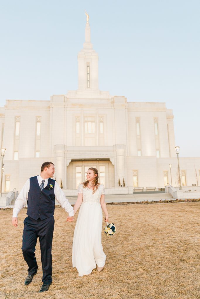 Jackson Hole wedding photographer captures Bride and groom walk from temple Chilly Pocatello Temple Bridals