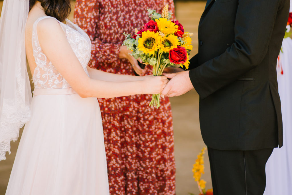 Jackson Hole wedding photographer captures Bride and groom holding hands at backyard idaho wedding ceremony