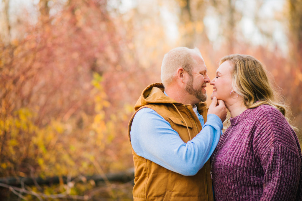 Jackson Hole wedding photographer captures man grabbing womans chin to pull her in for a kiss during fall engagement session