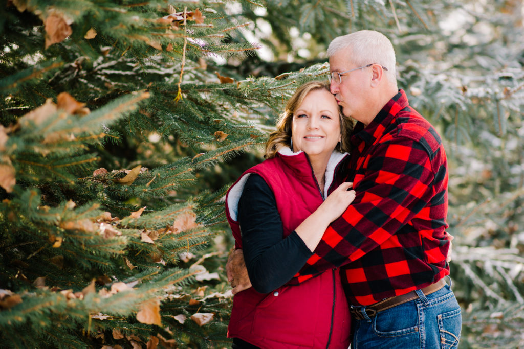 Jackson Hole wedding photographer captures Husband kissing wife on head by pine trees