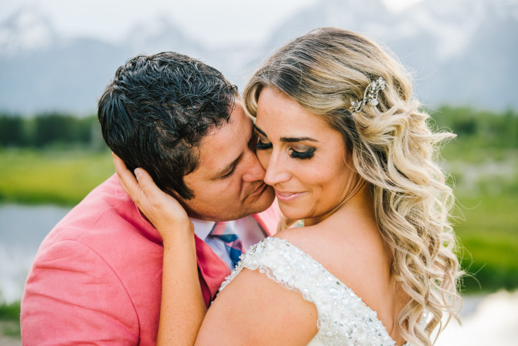 Jackson Hole wedding photographer captures groom kissing bride on cheek after getting married in Grand Teton National Park