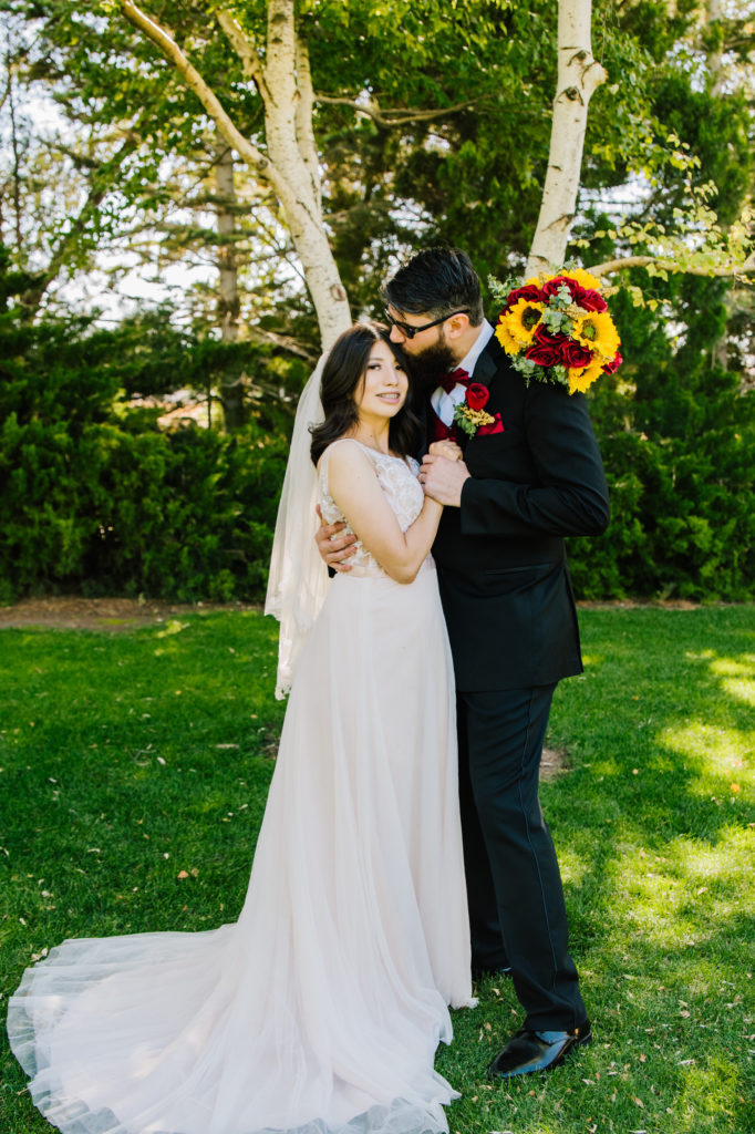 Jackson Hole wedding photographer captures groom kissing bride head with American Falls Photographer