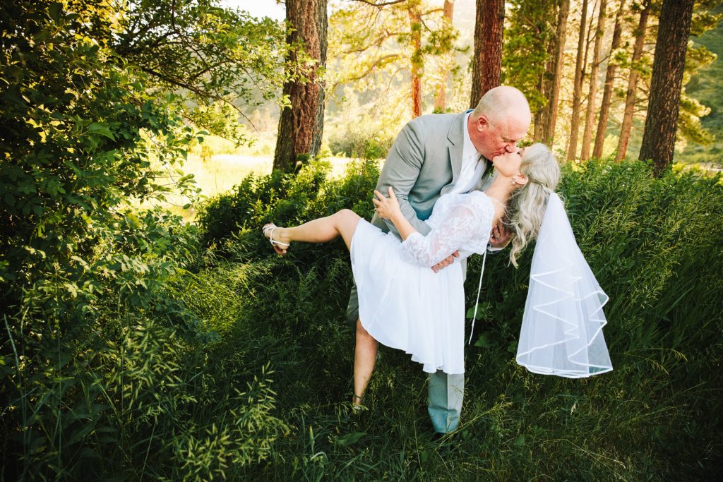 Jackson Hole wedding photographer captures Outdoor Pocatello Wedding Venue husband dips bride in wooded area