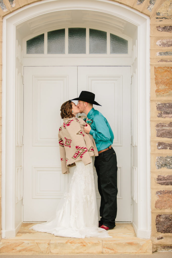 bride adn groom kissing one another in a doorway surrounded by old brick work in LDS temple 
