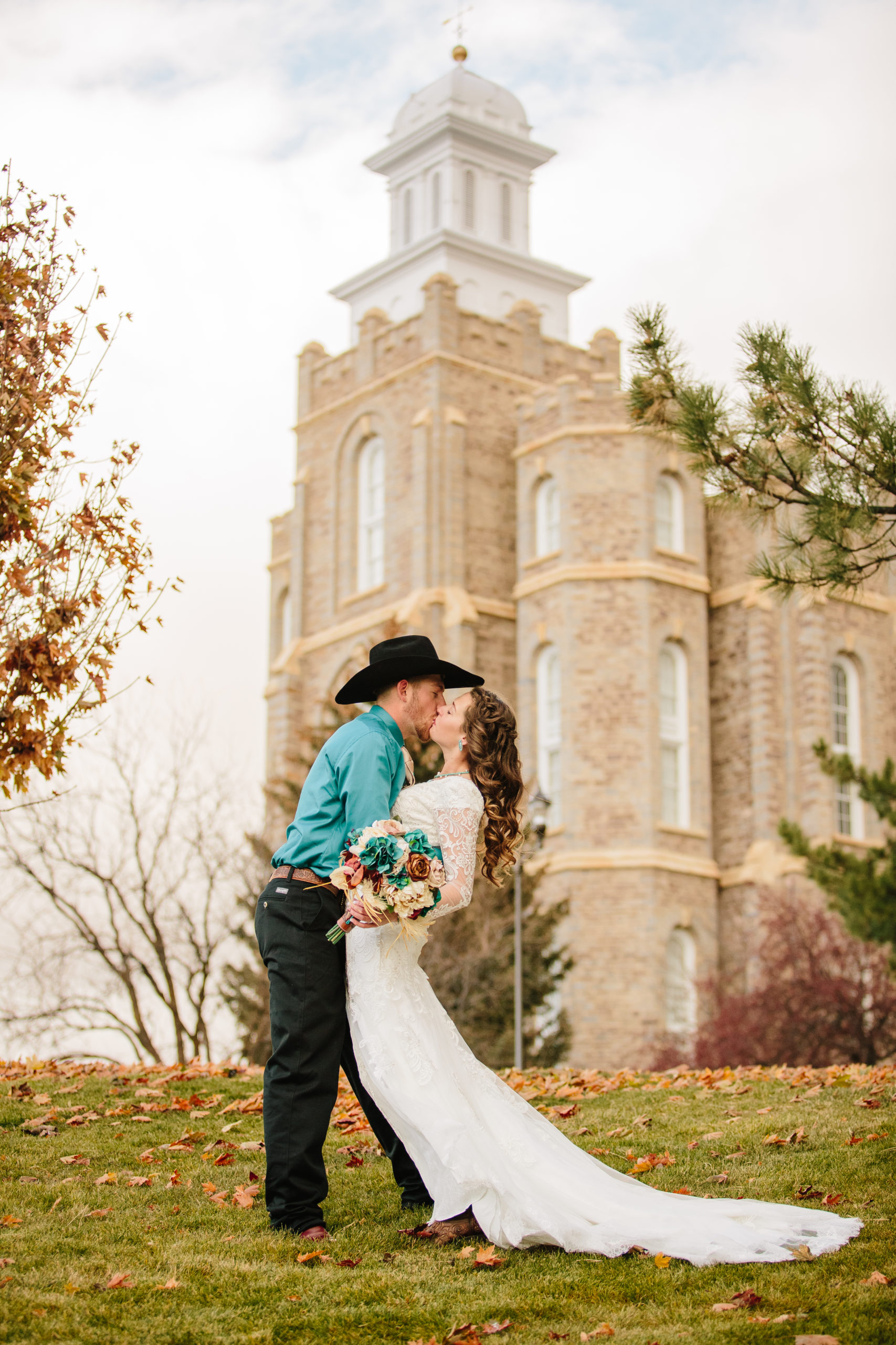 bride and groom kissing outside of the Logan Utah temple for their fall wedding day 
