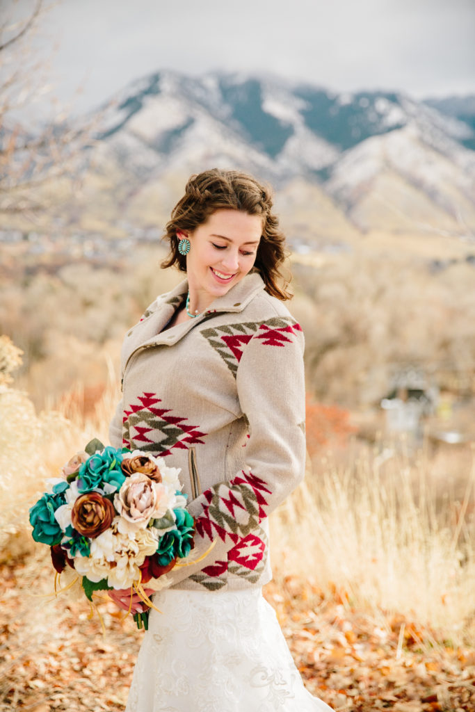 bride in a tribal pattern coat standing in a golden field for her bridal portraits with best Idaho photographer 