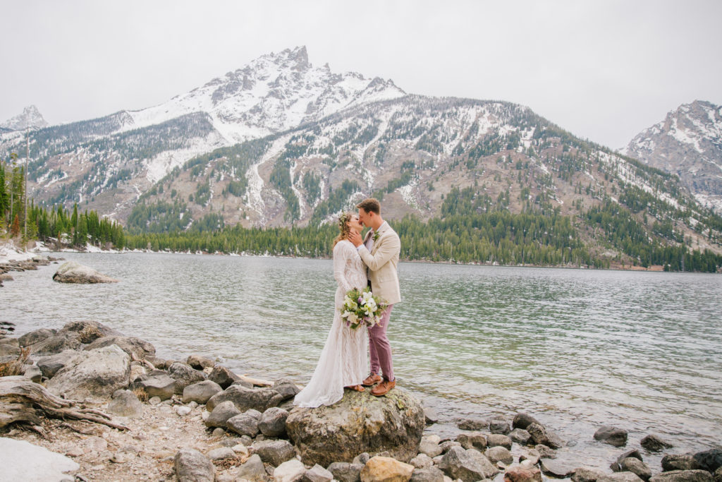 bride and groom kissing on rock during outdoor bridals in grand teton national park