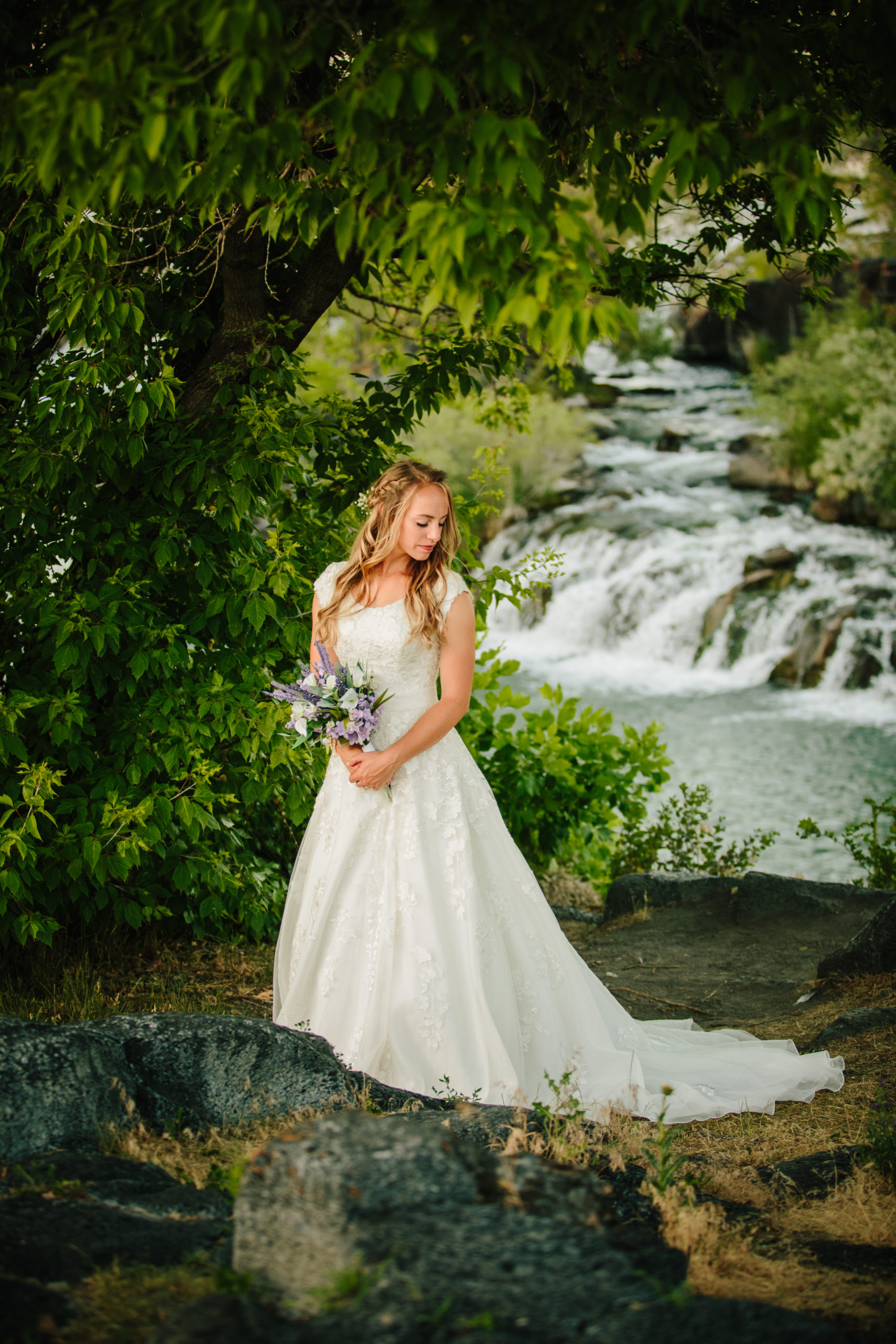 bride posing in her wedding gown with her wedding dress train behind her in a lush green forrest