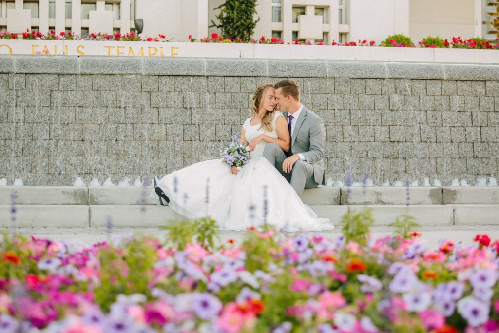 Jackson Hole wedding photographer captures beautiful idaho falls temple wedding bride and groom next to purple and pink flowers