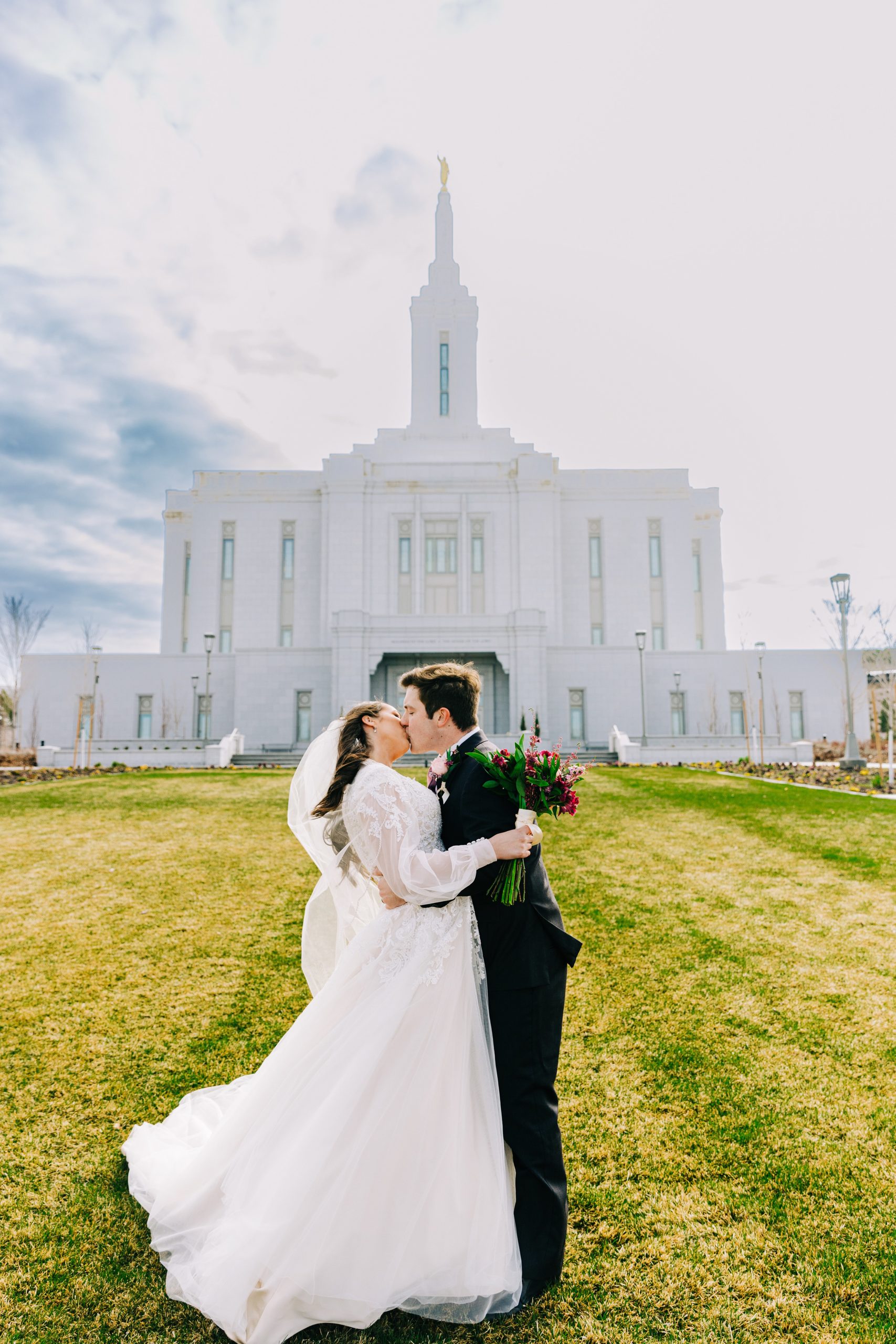 brides dress and veil flow in the wind on lds pocatello temple lawn