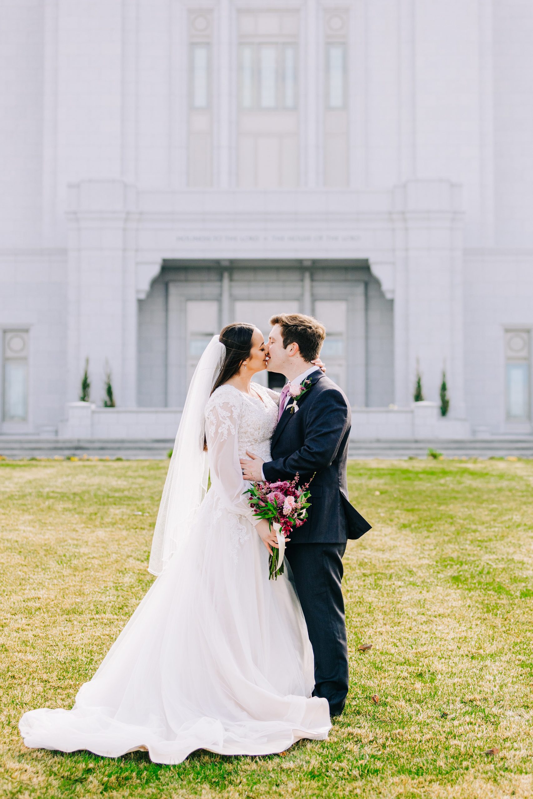 bride and groom kissing with bright shinning sun on lds temple lawn