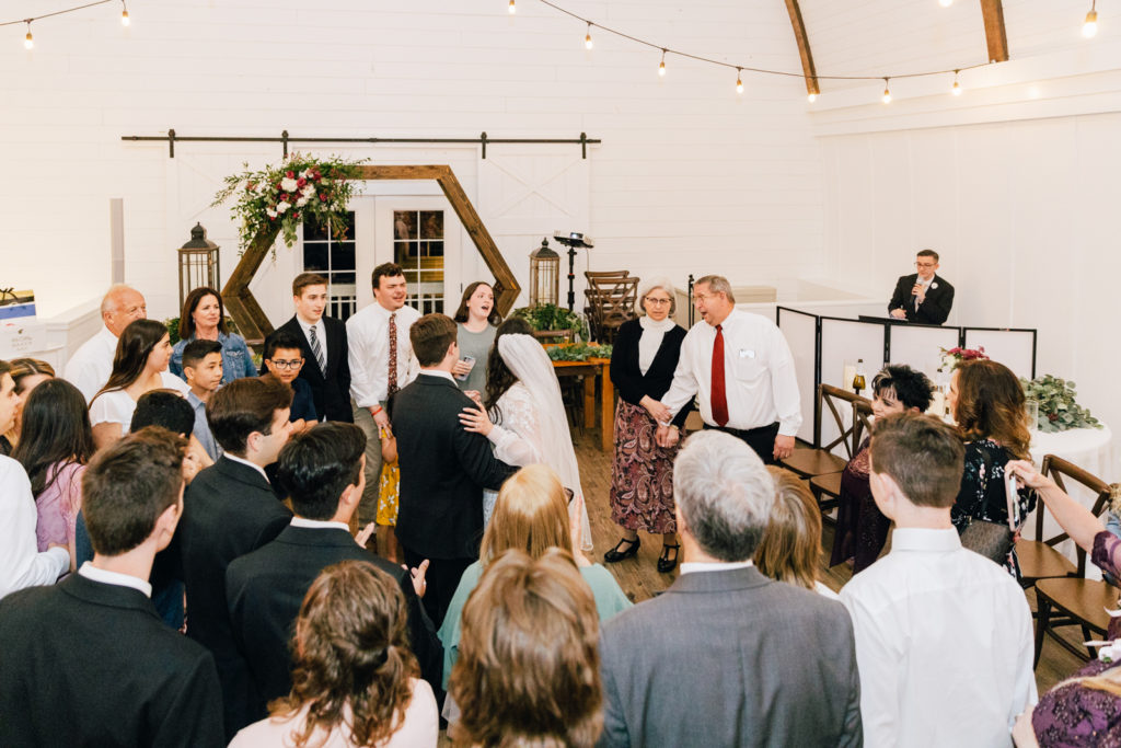 wedding reception in a white barn in Idaho Falls with wedding guest list dancing among the bride and groom