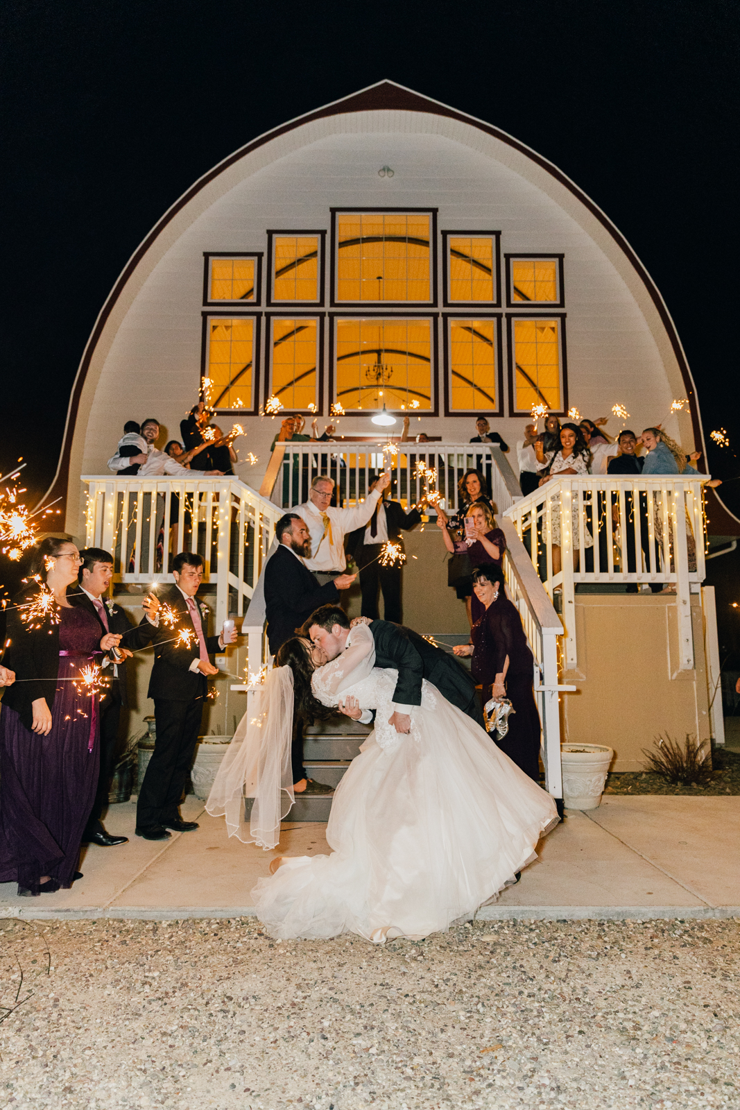 groom dipping bride backwards at their night time grand exit from their barn wedding in Pocatello Idaho