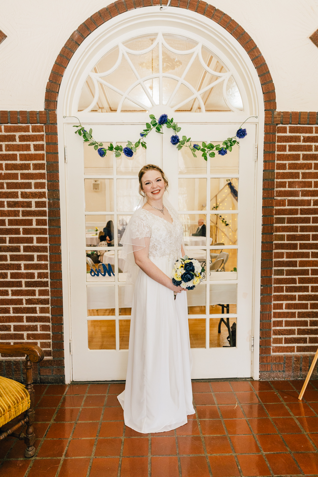 Jackson Hole wedding photographers capture bridal portrait of bride in her wedding reception holding her bouquet under and arched door way in Pocatello
