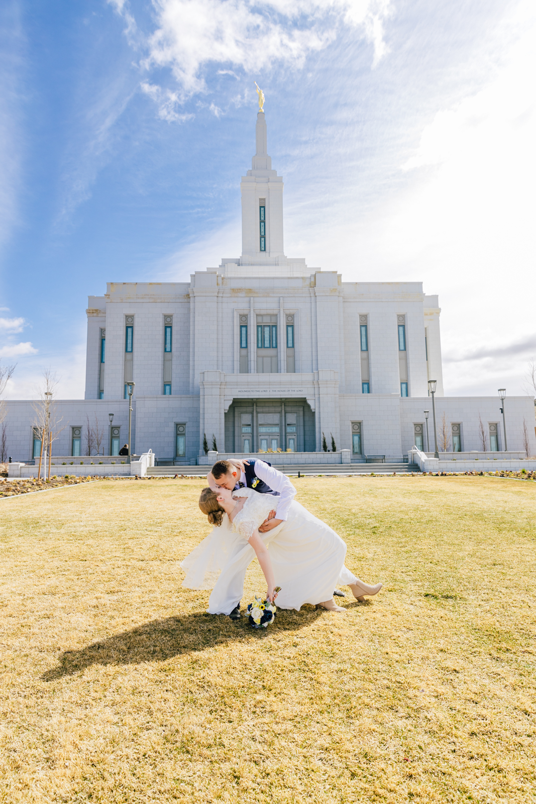 Jackson Hole wedding photographer capturesgroom kissing bride with pocatello idaho temple in background