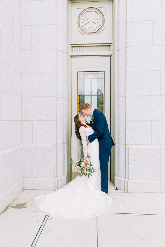 Jackson Hole wedding photographer captures bride and groom kissing in front of Idaho temple