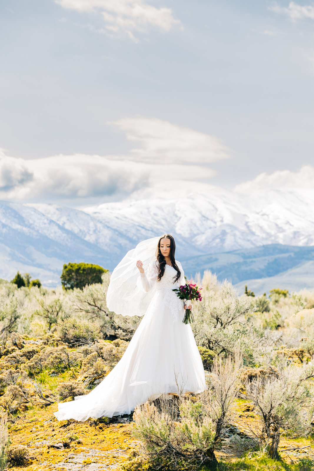 bride standing in a sage brush field as her veil blows in the wind during her bridal portraits with Jackson Hole wedding photographer 