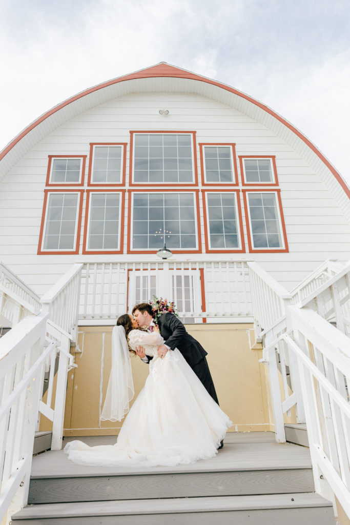 Jackson Hole wedding photographer captures bride and groom kissing in front of Barn on First wedding venue in Idaho Falls
