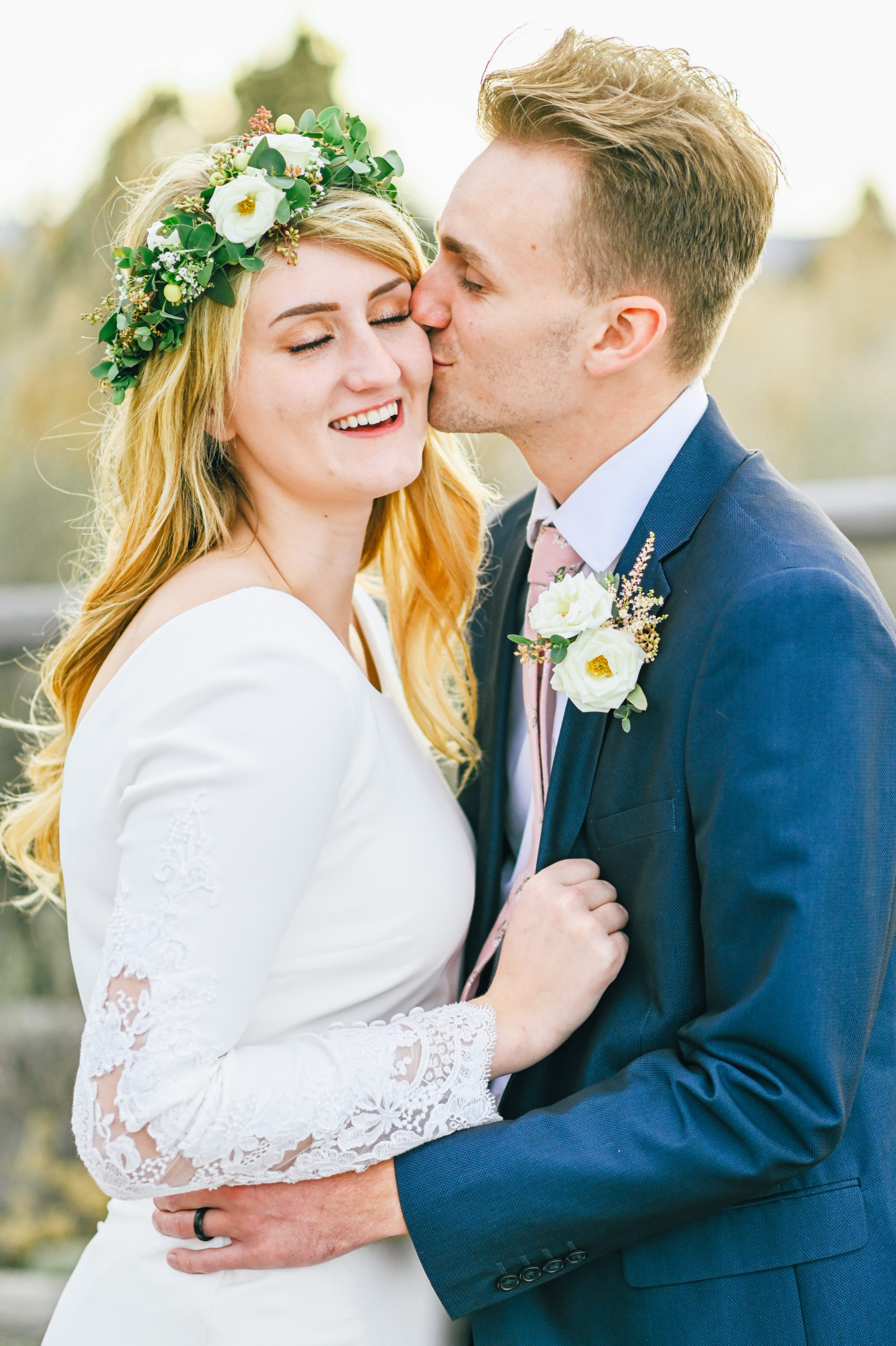 bride with eyes closed laughing as groom kissing bride's cheek