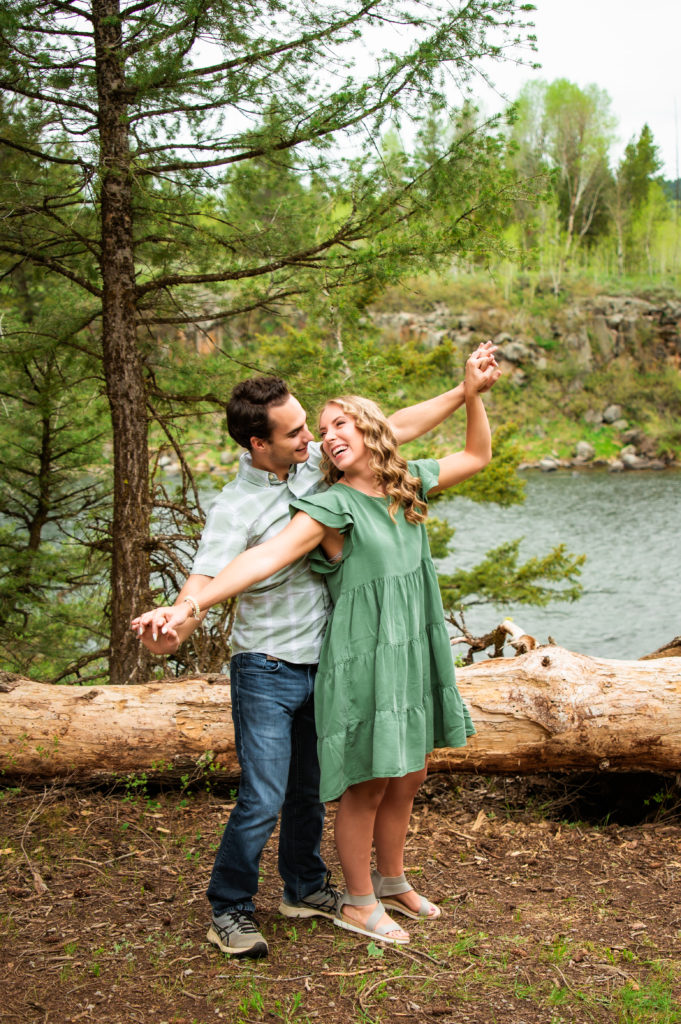 couple holding hands with arms outstretched during engagements