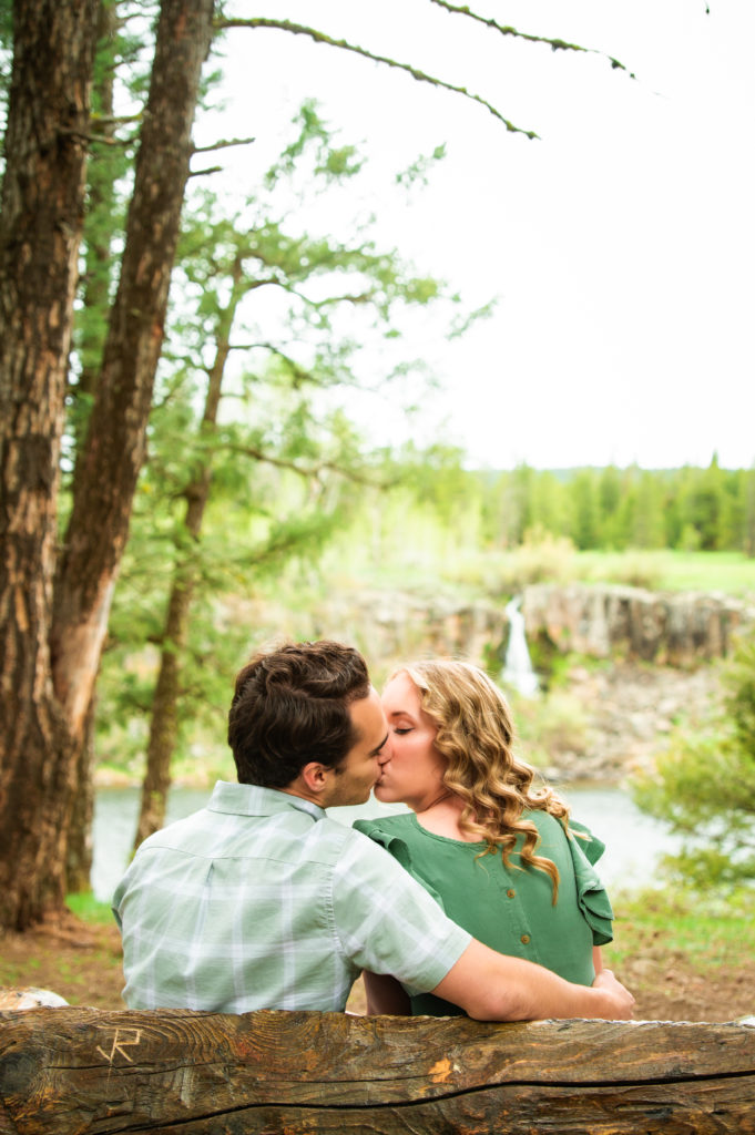 couple kissing on bench during engagement session
